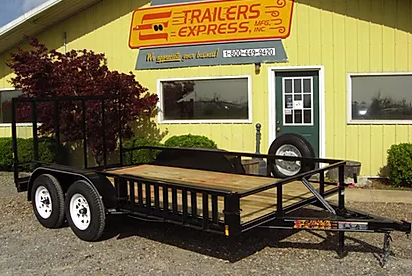 Black utility trailer parked outside a yellow Trailers Express building