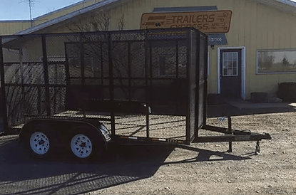 Black enclosed utility trailer with white wheels parked outside a building.