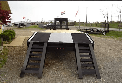 Black-and-gray stage ramp with stairs on both sides in an outdoor gravel lot