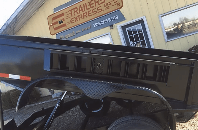 Black trailer with louvered side panel parked beside a building labeled “Trailer Express”