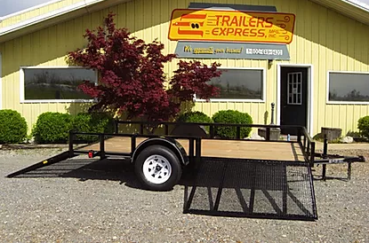 Black utility trailer with ramp parked outside a Trailers Express building.
