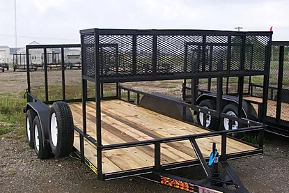 Black utility trailer with mesh sides and wooden floor parked on gravel outdoors