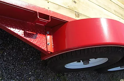 Red trailer fender and wheel on a gravel surface