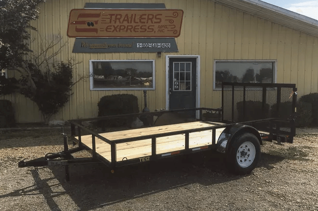 Utility trailer parked outside a building with a trailers express sign