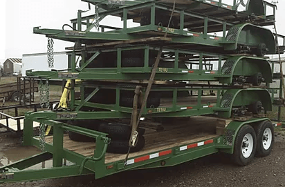 Stacked green metal frames on a flatbed trailer in a yard