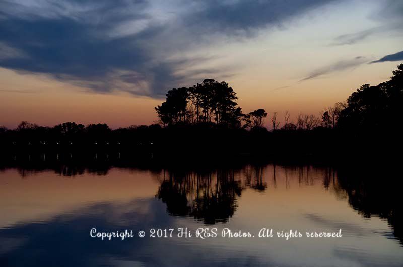 A sunset over a lake with trees in the background