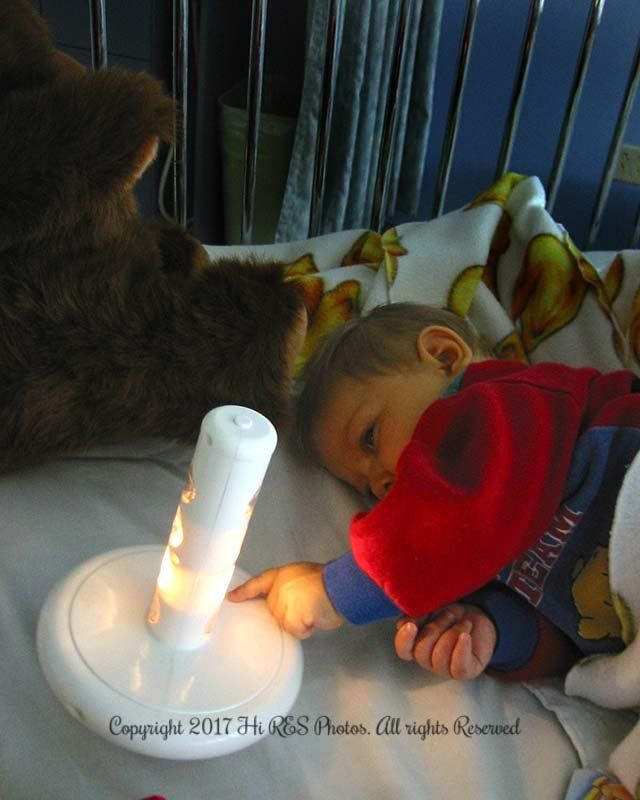 A baby in a superman shirt is playing with a light