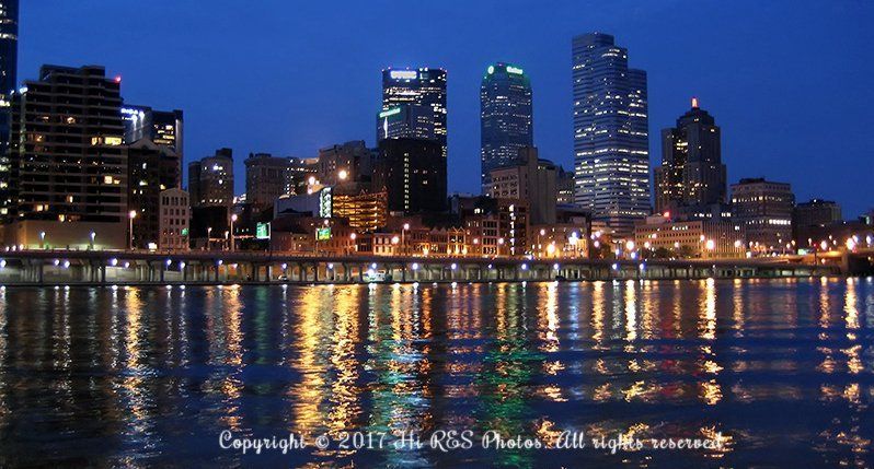 A city skyline is reflected in the water at night