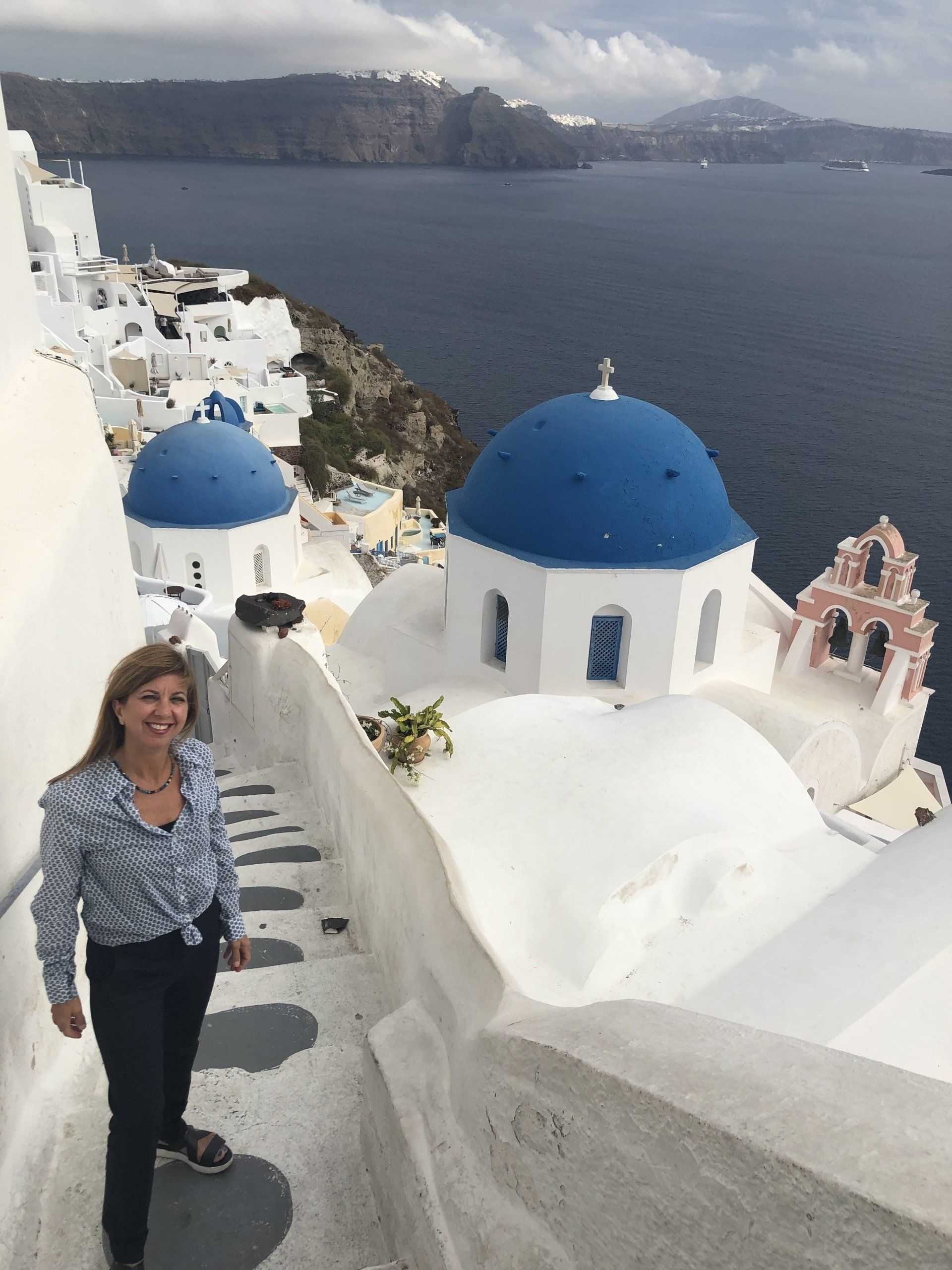 A woman is standing in front of a white building with a blue dome on top