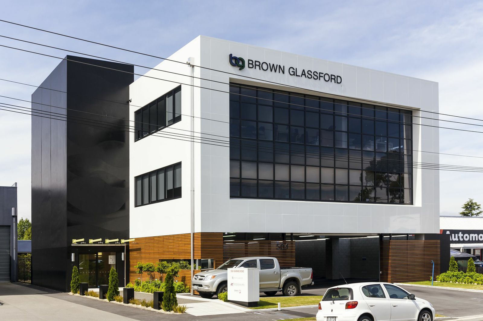 A white car is parked in front of a large building.
