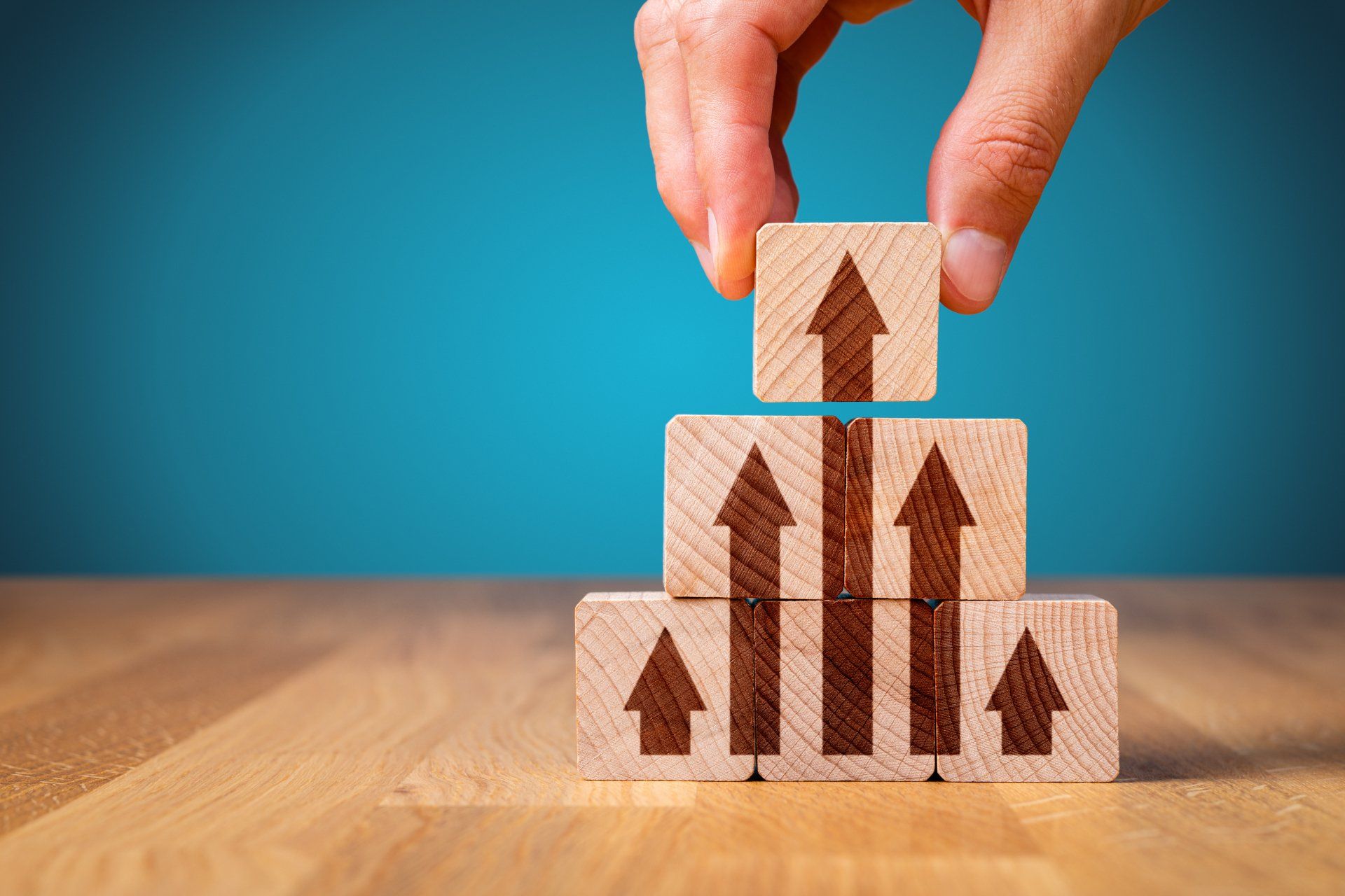 A person is stacking wooden blocks with arrows on them.