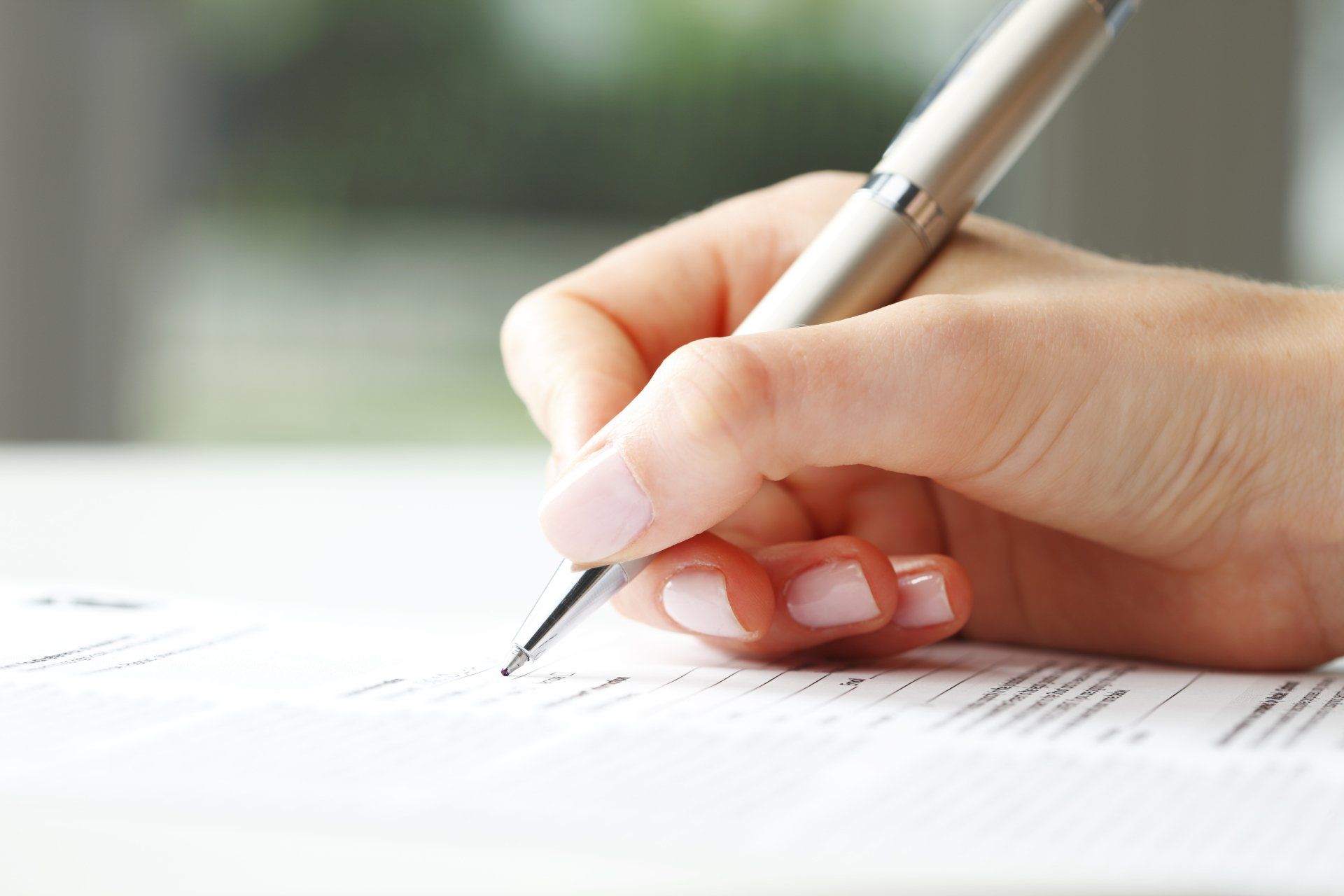 A woman is writing on a piece of paper with a pen.
