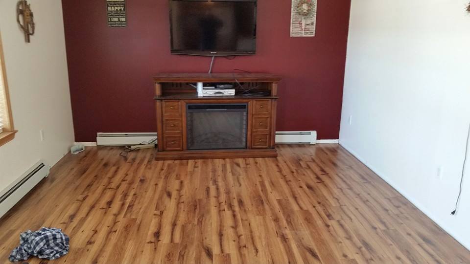 A living room with hardwood floors , a fireplace and a flat screen tv.