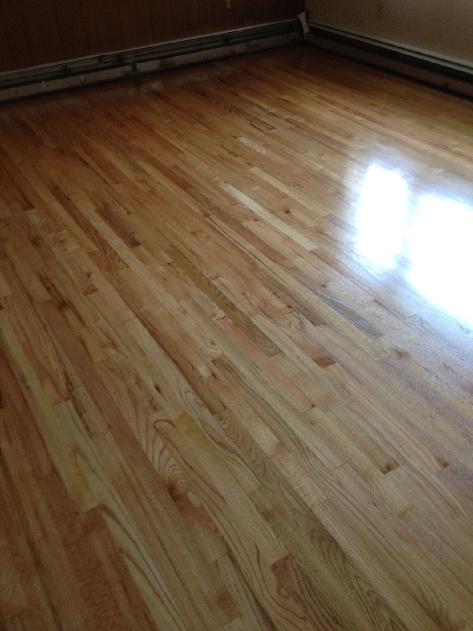 A wooden floor in a room with a reflection of light on it.