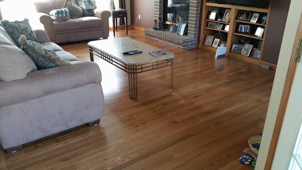 A living room with hardwood floors , a couch , chair , coffee table and fireplace.