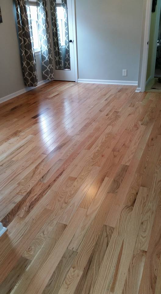 A living room with hardwood floors and two windows.