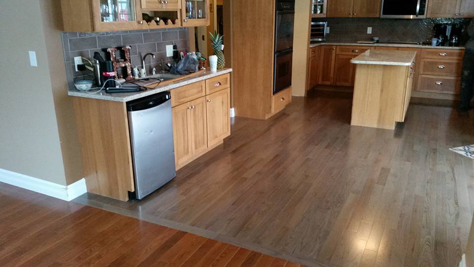 A kitchen with wooden cabinets , stainless steel appliances , and hardwood floors.