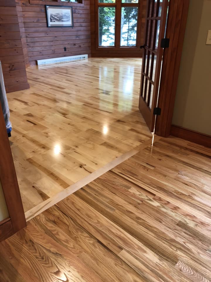 A wooden floor in a room with a door and a picture on the wall.