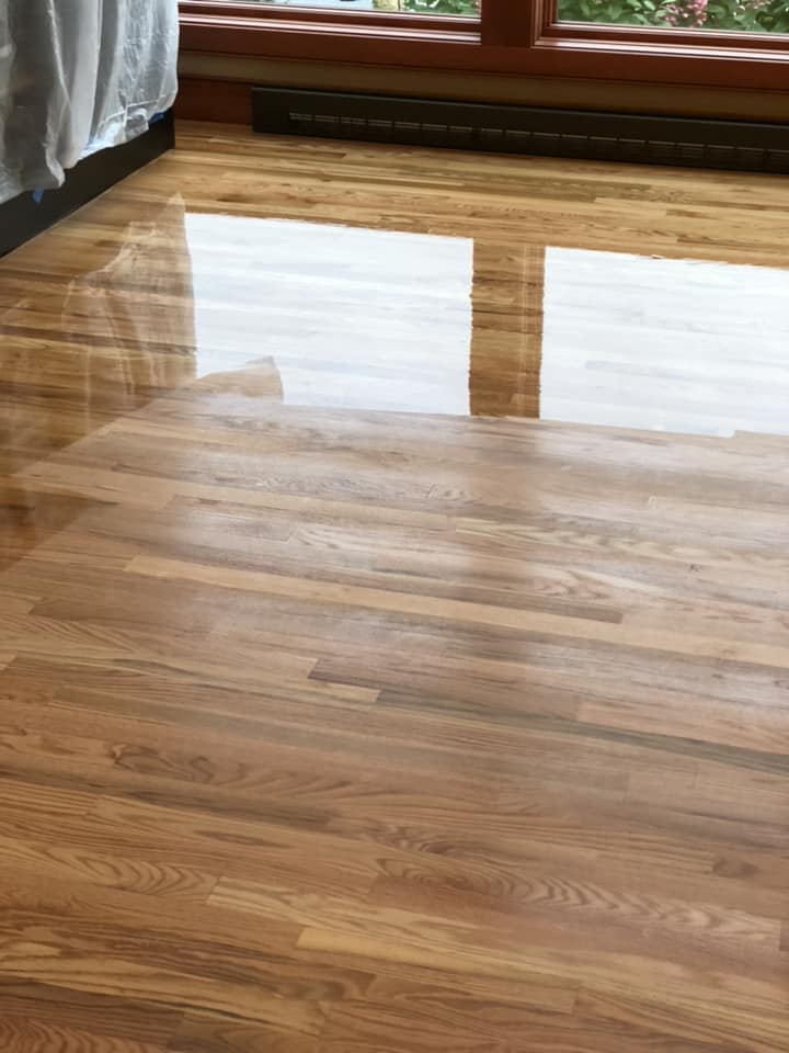 A close up of a wooden floor with a window in the background.