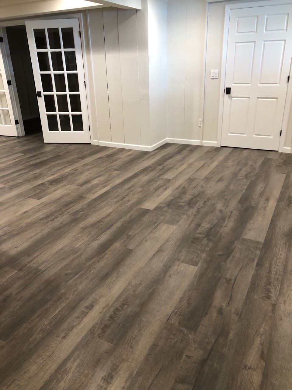 A basement with hardwood floors and white doors.