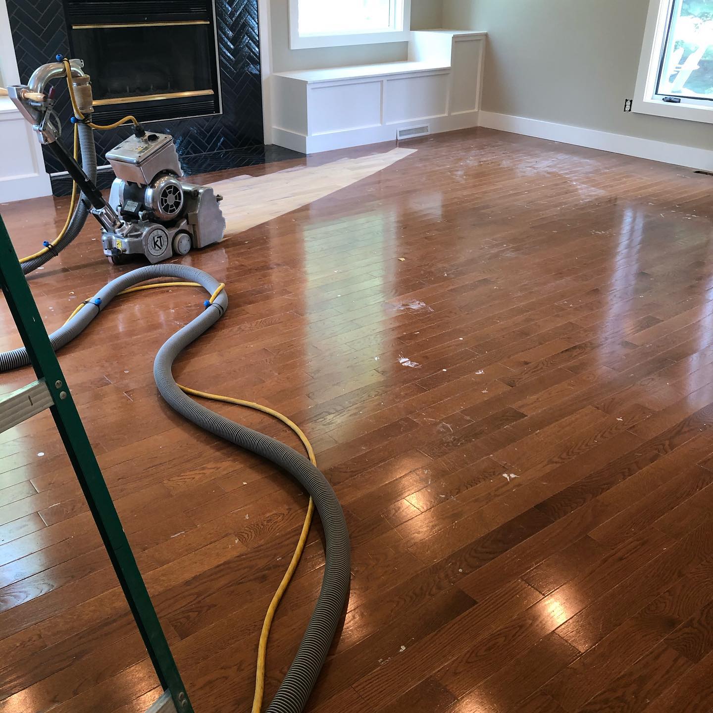 A machine is sanding a wooden floor in a living room.