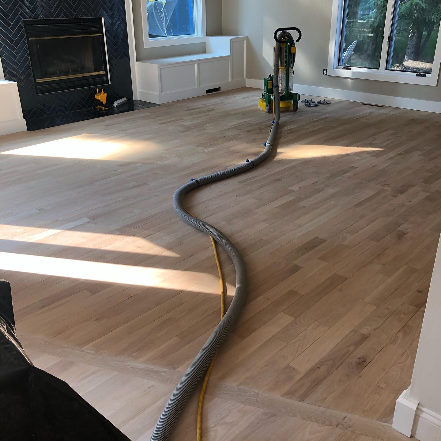 A vacuum cleaner is sitting on a wooden floor in a living room.