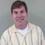 A man in a yellow striped shirt is smiling for the camera.