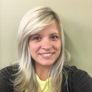 A woman with blonde hair and a yellow shirt is smiling for the camera.