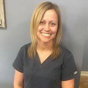 A woman in a scrub top is smiling for the camera.