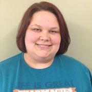 A woman wearing a blue t-shirt is smiling for the camera.