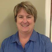 A woman in a blue shirt is smiling for the camera.
