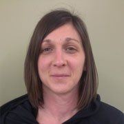 A woman with brown hair and a black shirt is smiling for the camera.