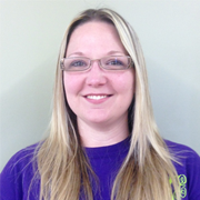 A woman wearing glasses and a purple shirt is smiling for the camera.