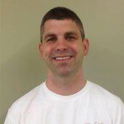 A man in a white shirt is smiling for the camera.