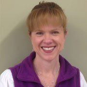 A woman is wearing a purple vest and smiling for the camera.