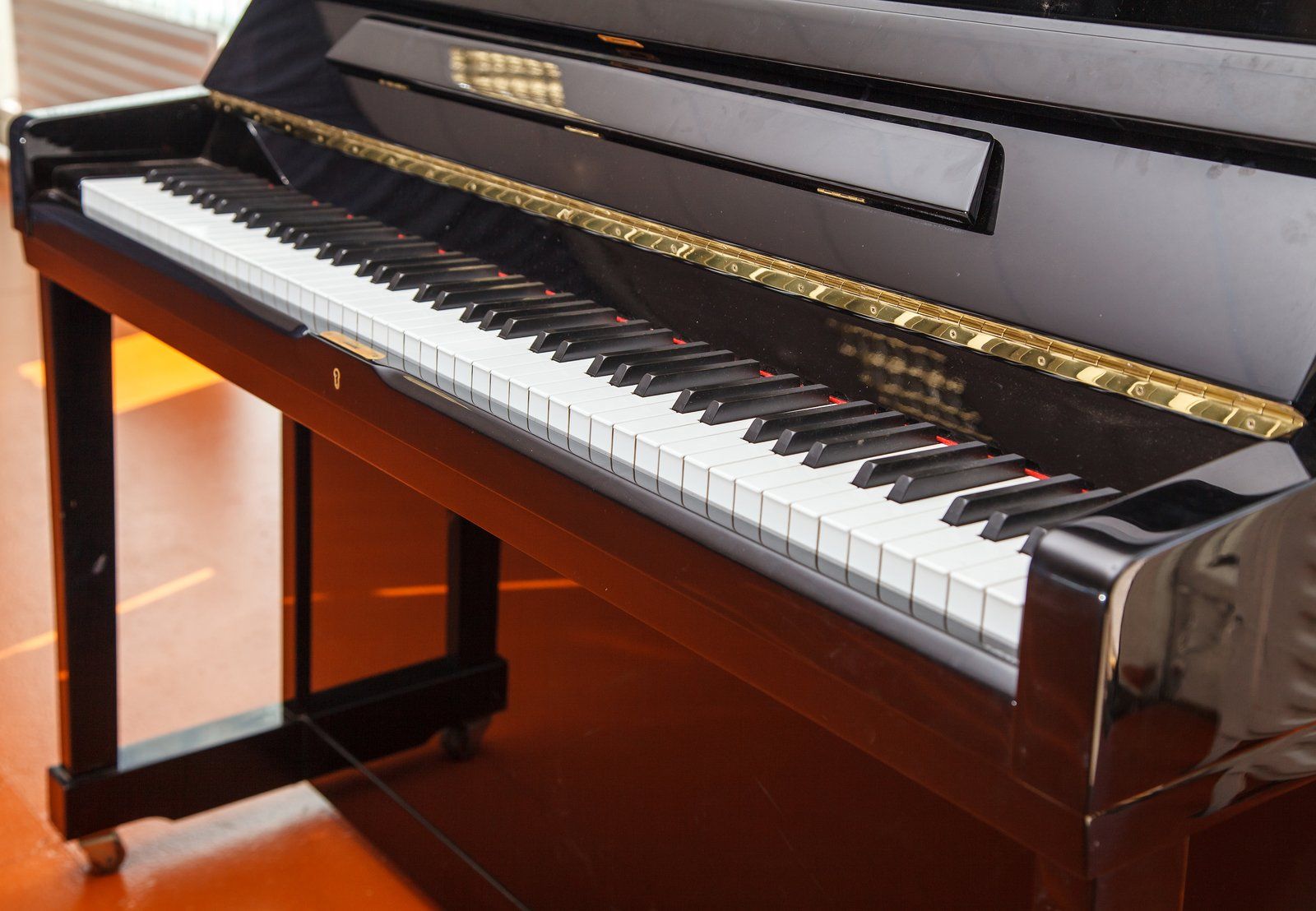 Black upright piano with white and black keys, gold trim.