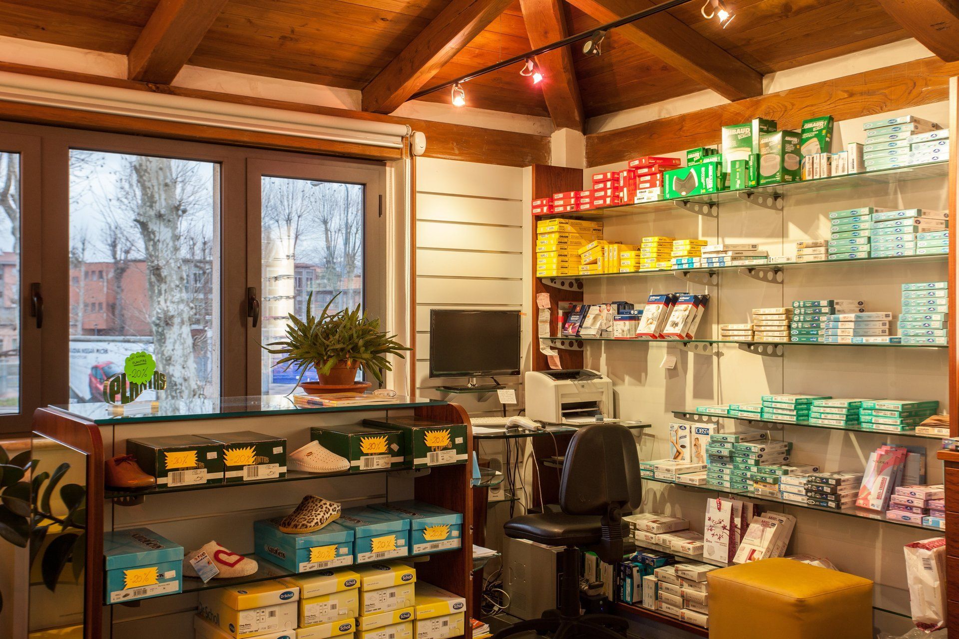 L'interno di una farmacia con un bancone di vetro pieno di scatole di scarpe e scaffali che espongono un assortimento di prodotti medici e di vendita al dettaglio.