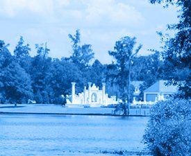 A blue and white photo of a lake with trees in the foreground