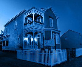 A blue and white photo of a house with a white picket fence