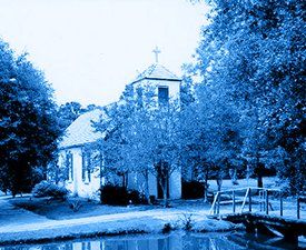A blue and white photo of a church with a cross on top
