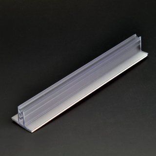 Un portaetiquetas para borde de estante fabricado con plástico transparente y metal sobre una superficie negra.