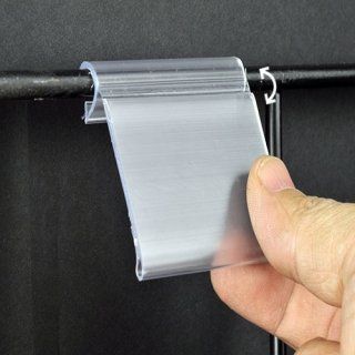Porta carteles de plástico transparente fijado a una barra de metal negra; mano sujetando el cartel.