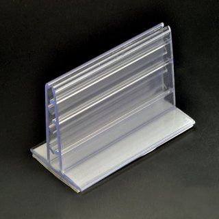 Porta carteles de plástico transparente, en forma de T con base, sobre superficie negra.