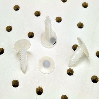 Tres sujetadores de plástico blanco con cabezas circulares sobre un exhibidor perforado