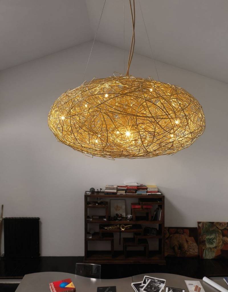 Una lampada dorata intrecciata è appesa sopra una libreria in legno scuro in una stanza dalle pareti bianche.