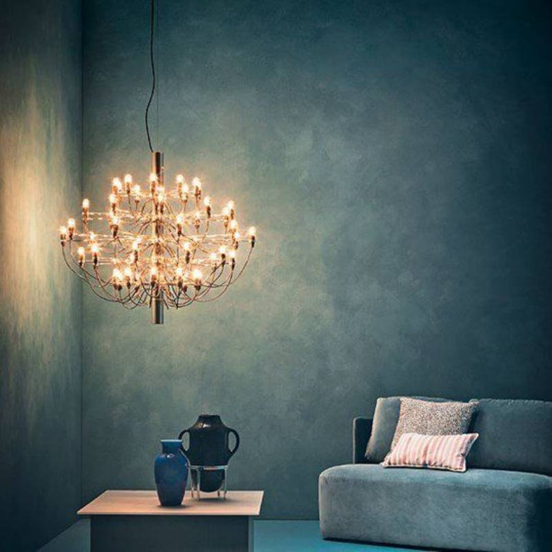 Un grande lampadario illumina una stanza dalle pareti color verde acqua, arredata con un divano e dei vasi.