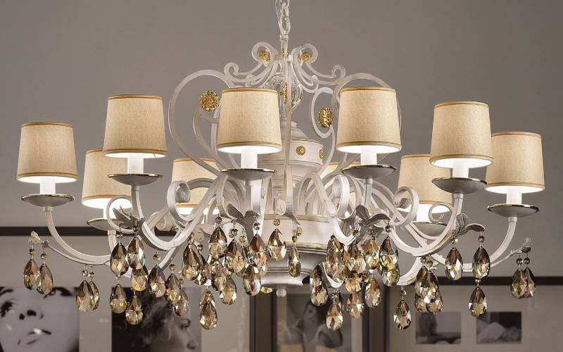 Lampadario bianco e oro con paralumi beige e dettagli in cristallo.