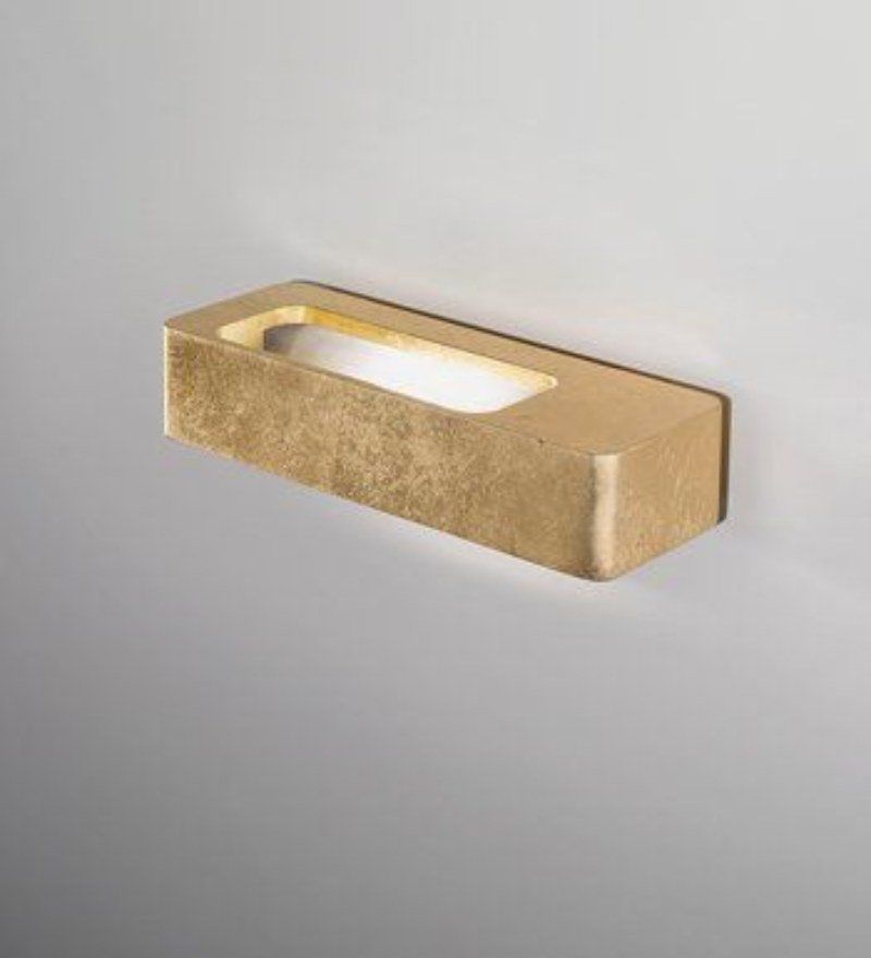 Applique rettangolare color oro con un'apertura rettangolare centrale illuminata, montata su una parete grigia.