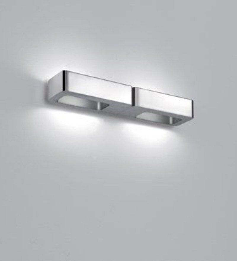 Lampada da parete rettangolare color argento con due luci incassate che emettono una luce intensa su una parete bianca.