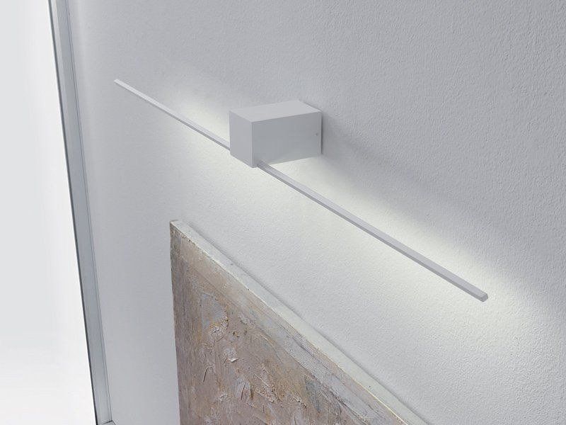 Lampada da parete bianca con base rettangolare e lungo braccio orizzontale che illumina il dipinto sottostante.